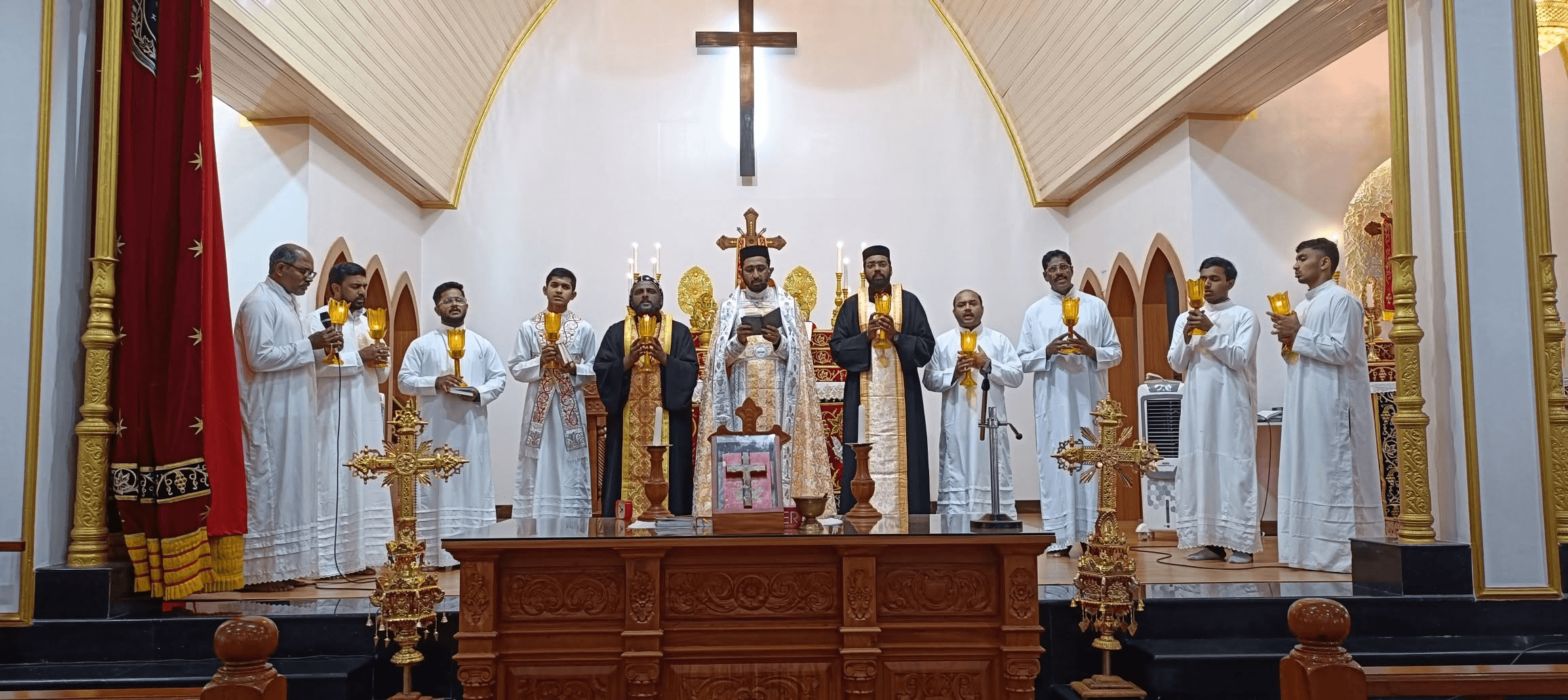 Clergy bearing lit lamps before the altar during a festal service