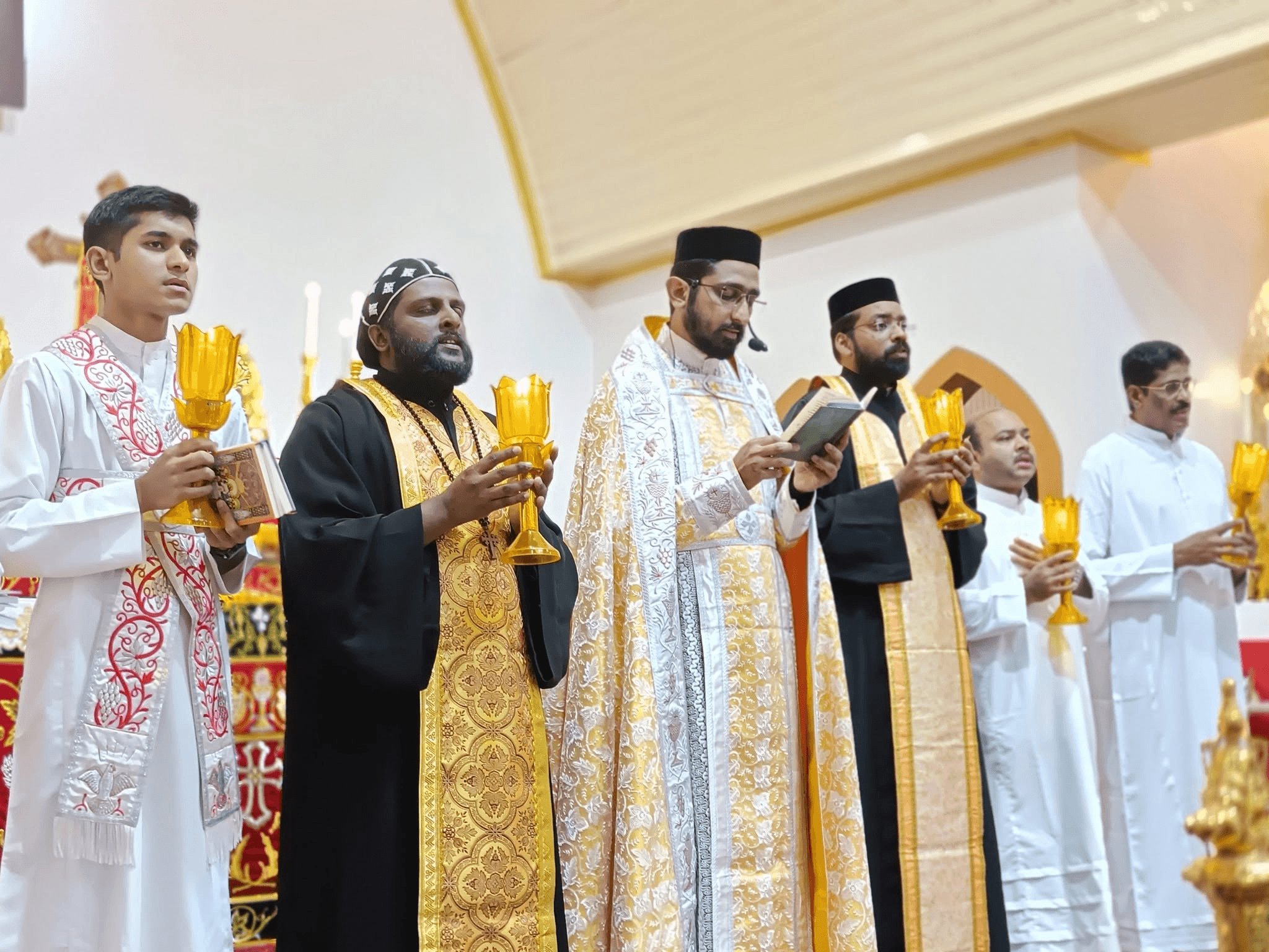 Clergy in vestments holding lit lamps during the Holy Qurbana